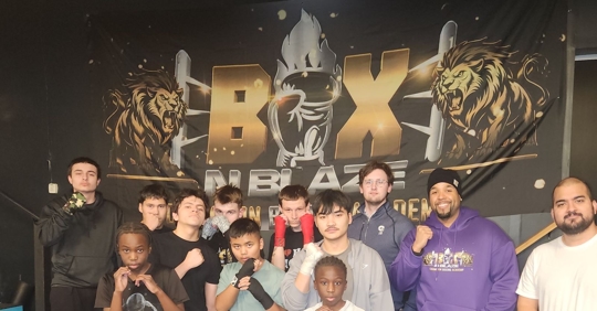 A group of boxers and a lawyer standing in front of a banner reading "Boxnblaze"